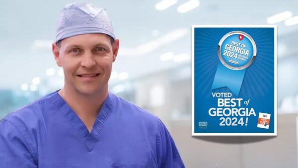 Person in medical scrubs standing next to a 'Voted Best of Georgia 2024' sign.