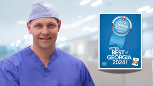 Person in medical scrubs standing next to a 'Voted Best of Georgia 2024' sign.