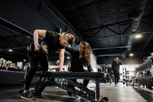 Person lifting weights with a personal trainer in a gym setting